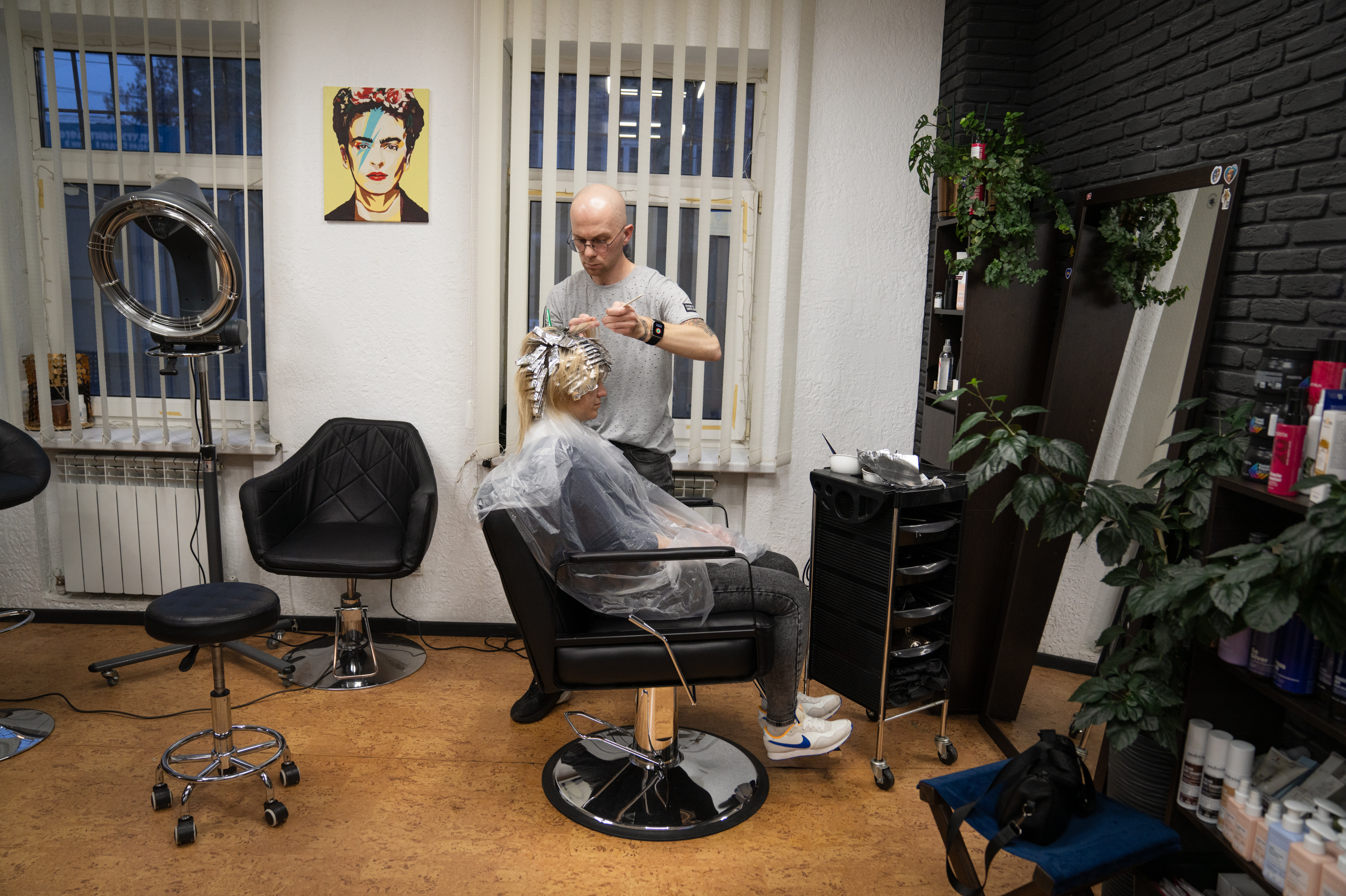 As Ukraine seeks to replenish its depleted army, a divide grows among its civilians 4 Yevhen Shcherbyna, a hairdresser in Dnipro, colors a woman's hair at his salon downtown. He hears from many clients that they're worried their family members will be conscripted.