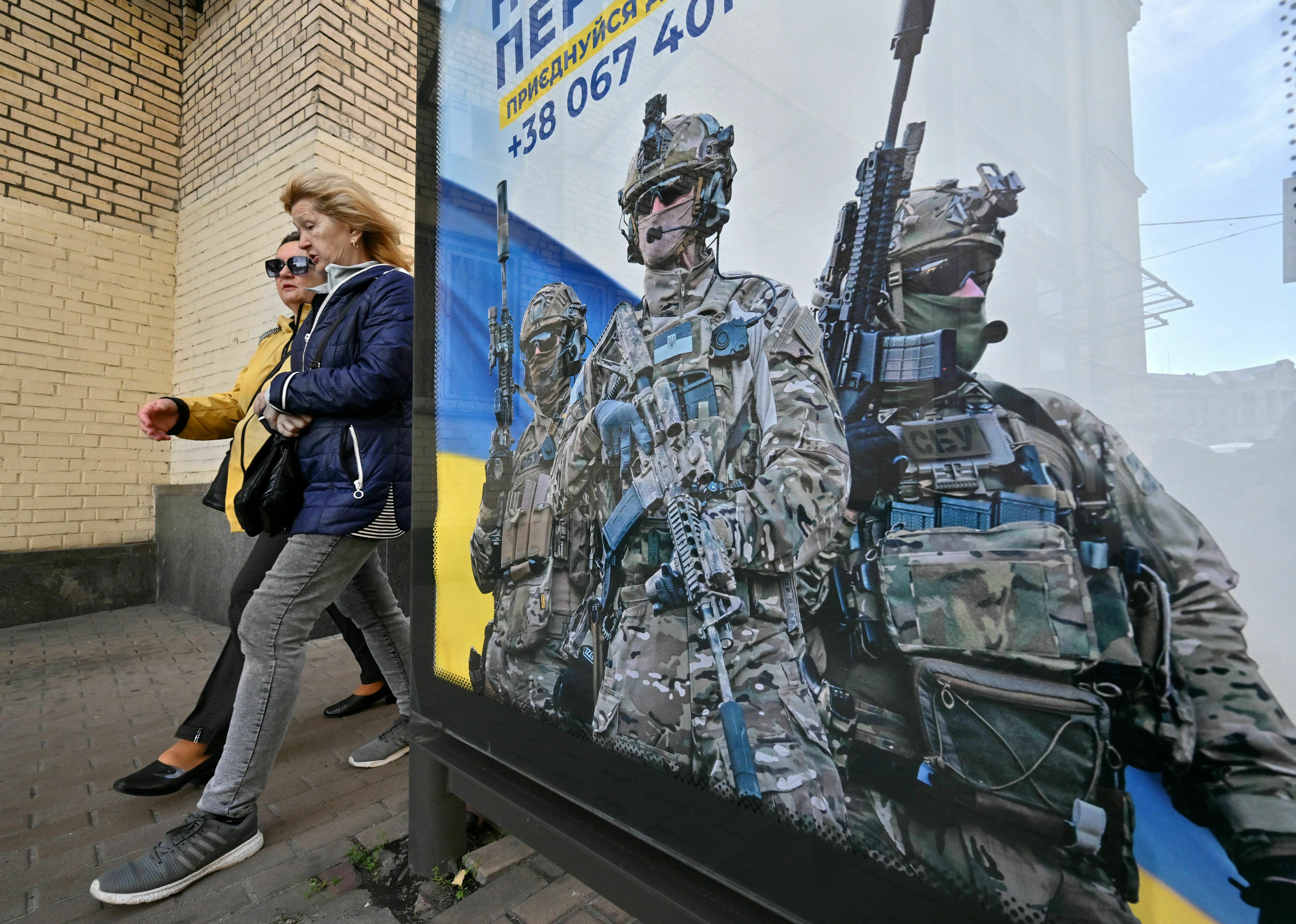 As Ukraine seeks to replenish its depleted army, a divide grows among its civilians 3 Pedestrians in Kyiv walk past a poster depicting Ukrainian servicemen and a slogan that reads, "Bring the victory soon," on Oct. 31.
