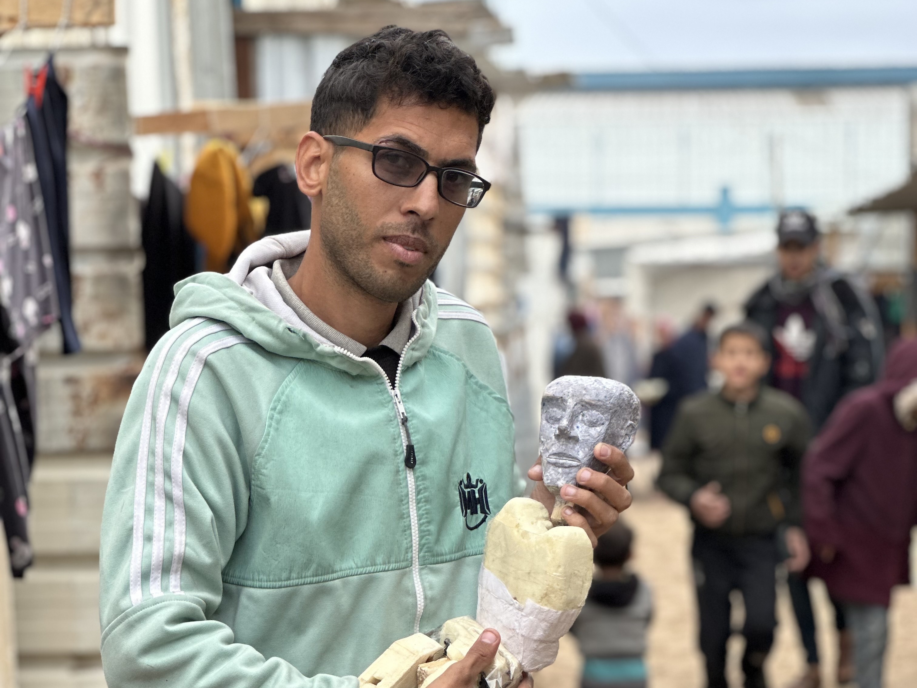 Yousef al-Hindi holds a puppet, also named Yousef, that he created using materials found in his camp in Rafah. (NPR)
