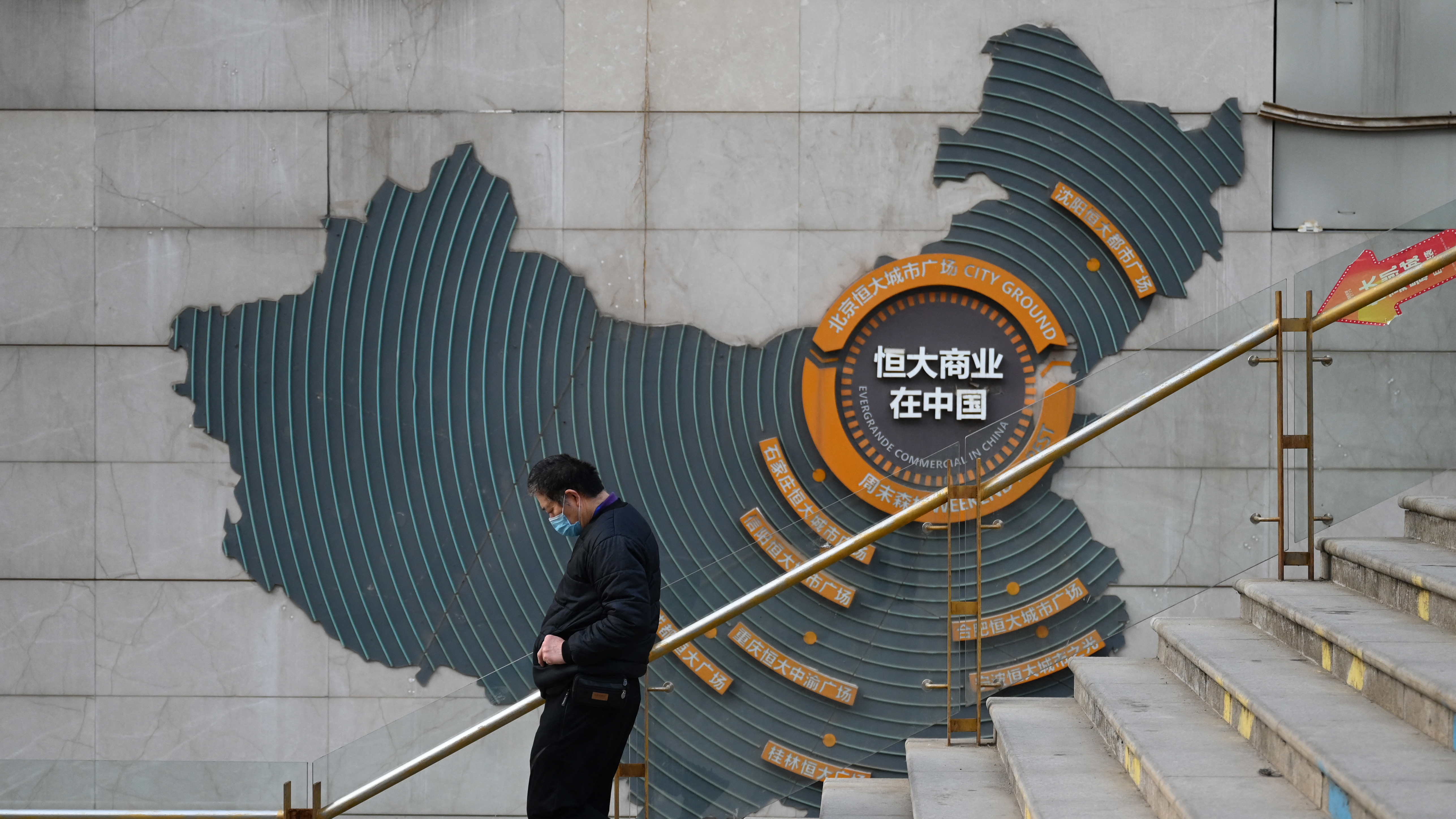 At a partially operating Evergrande commercial complex in Beijing on Monday, a man walks past a map of China that shows Evergrande