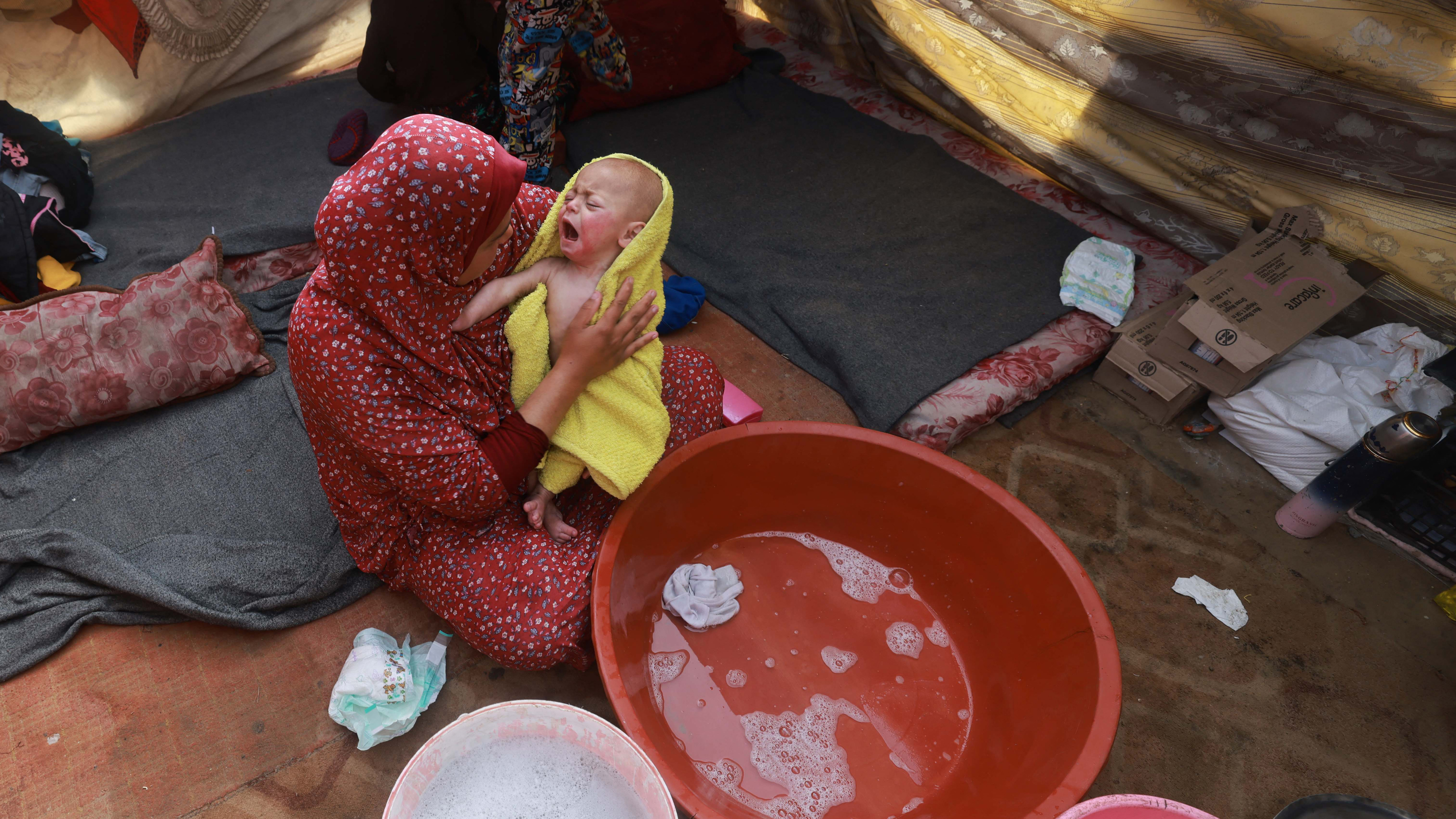 A woman dries a baby in a towel after giving the infant a bath inside a tent at a camp for displaced Palestinians in Rafah, in southern Gaza, on Jan. 18.