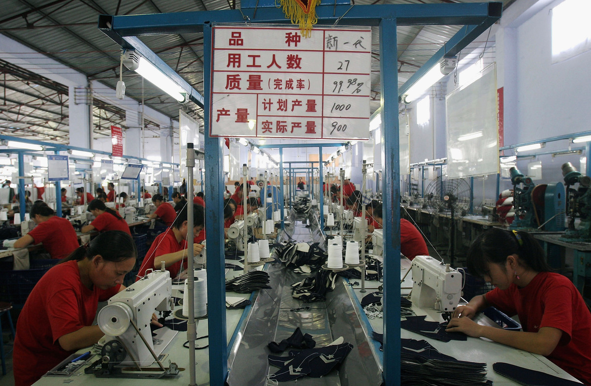 2005 年 8 月 13 日,中国成都的一家工厂里,工人们正在生产运动鞋零件。