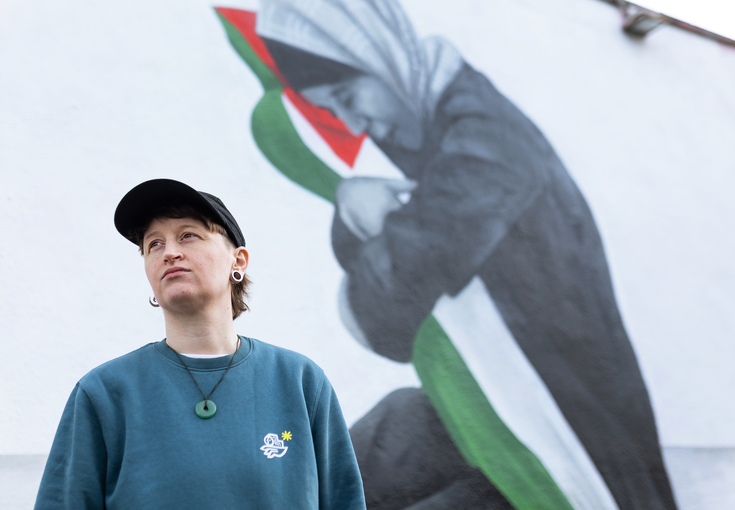 Emmalene Blake poses for a portrait in front of her mural showing Samia al-Atrash holding her niece Masa Khader, who was killed by an Israeli airstrike in Gaza in October. (Molly Keane for NPR)