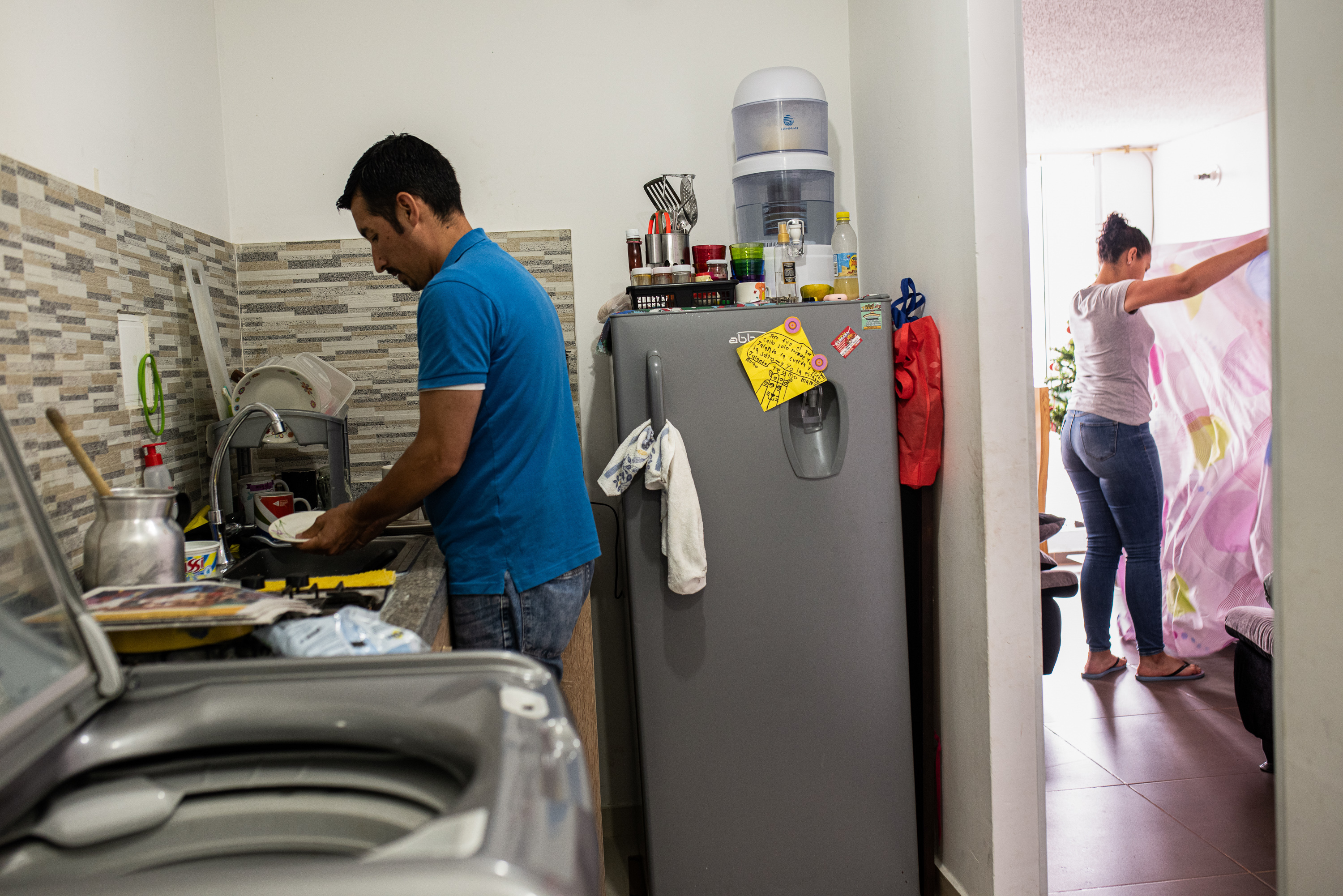 Hey, guys, wanna know how to diaper a baby or make a ponytail? Try the School for Men 7 Ferley Sáenz and his wife, María Alejandra López, now divide up household chores. Here, Sáenz washes the dishes while López tidies up the living room.