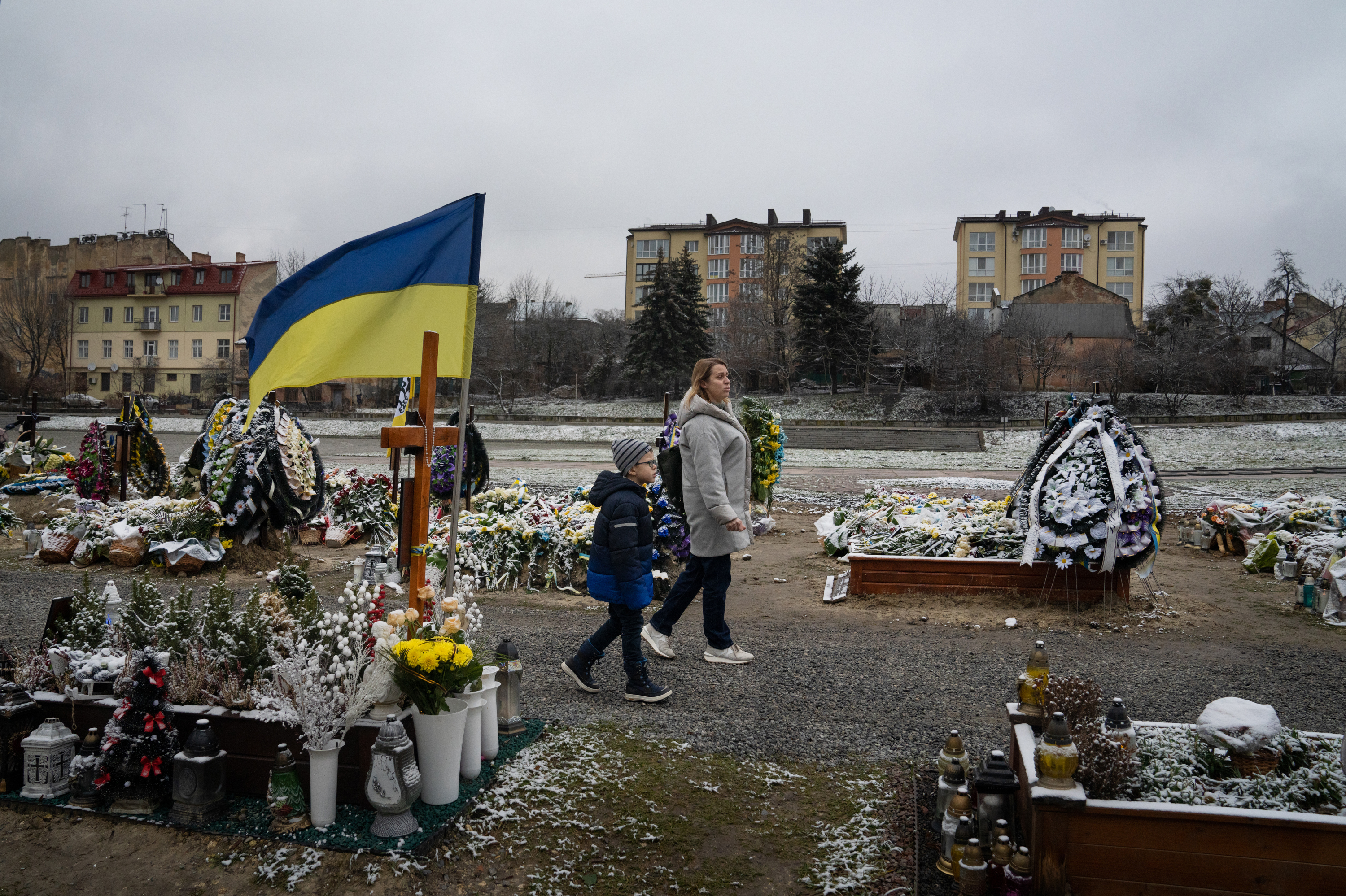 Bohdan Semenukha and his mother, Viktoria, walk frequently through the Lychakiv cemetery in Lviv, Ukraine, just a few blocks from the new apartment where they moved after fleeing Kharkiv, in the country's northeast, in January 2023. (NPR)