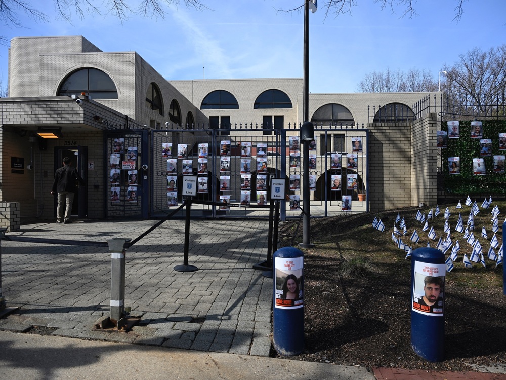A man enters the Israeli embassy, near pictures of hostages in Gaza, in Washington, D.C., on Monday. An airman has died after self-immolating in what he said on social media was an act of protest against Israel's war in Gaza. (AFP via Getty Images)