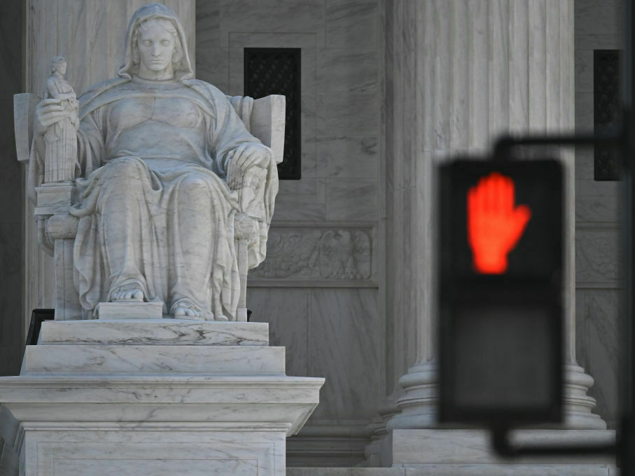 The Supreme Court, seen behind the stop light, is hearing arguments in a case testing the legality of a federal regulation banning devices that modify semiautomatic weapons to speed the firing mechanism. (AFP via Getty Images)