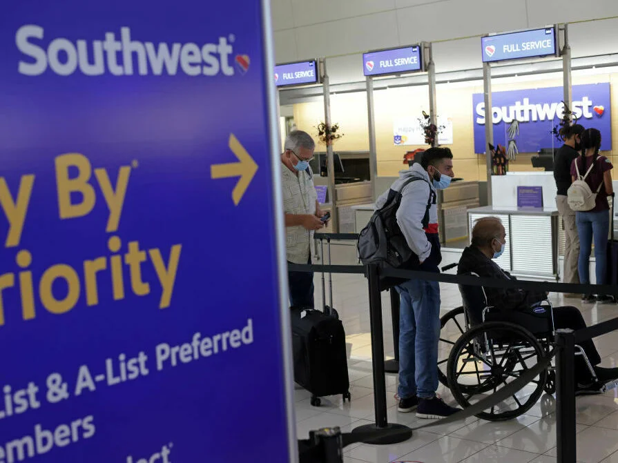 Southwest check in counter with several passengers waiting, including one in a wheelchair.