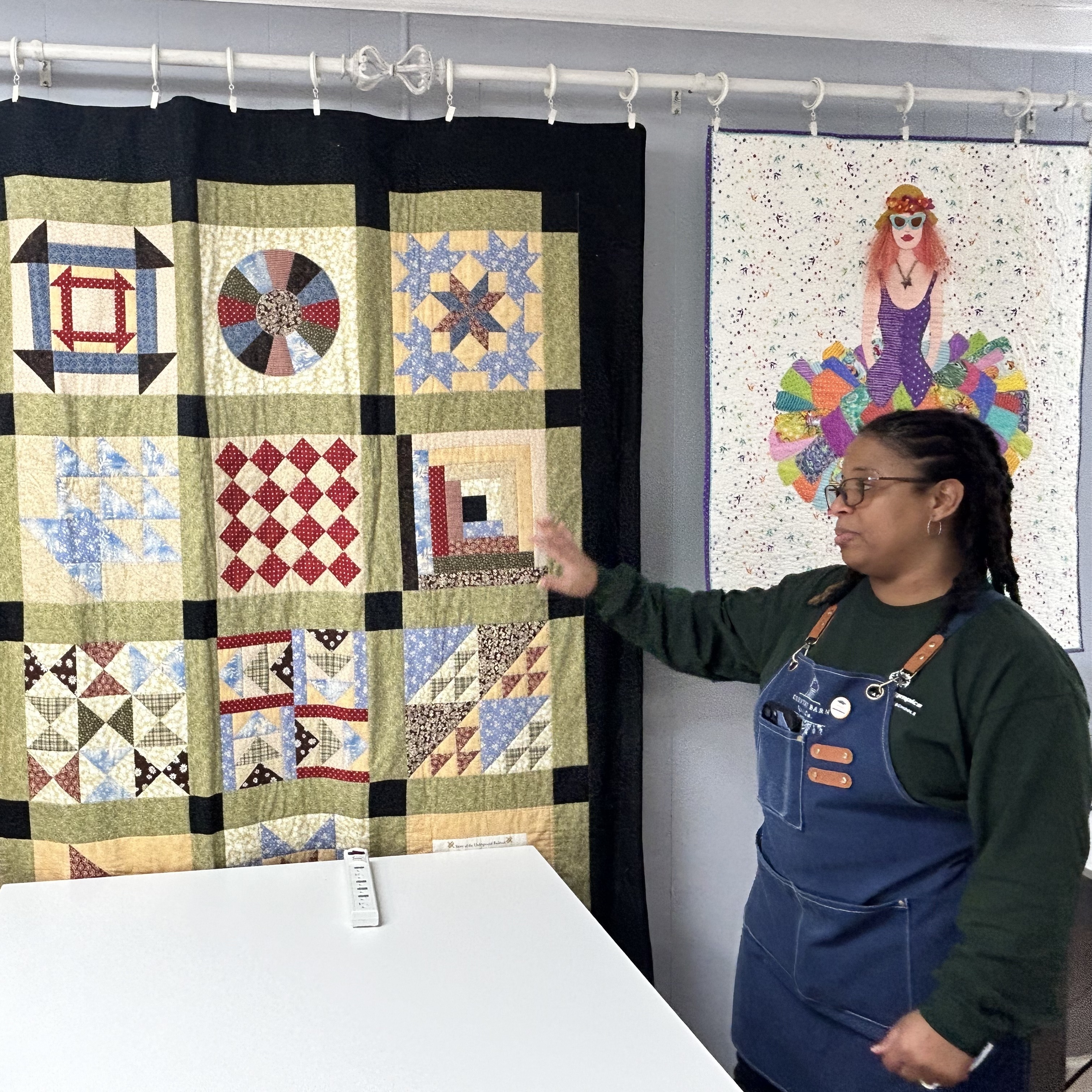 Sandra Daniel stands before an Underground Railroad Quilt Code quilt hanging in her store, Country Barn Quilt Co.