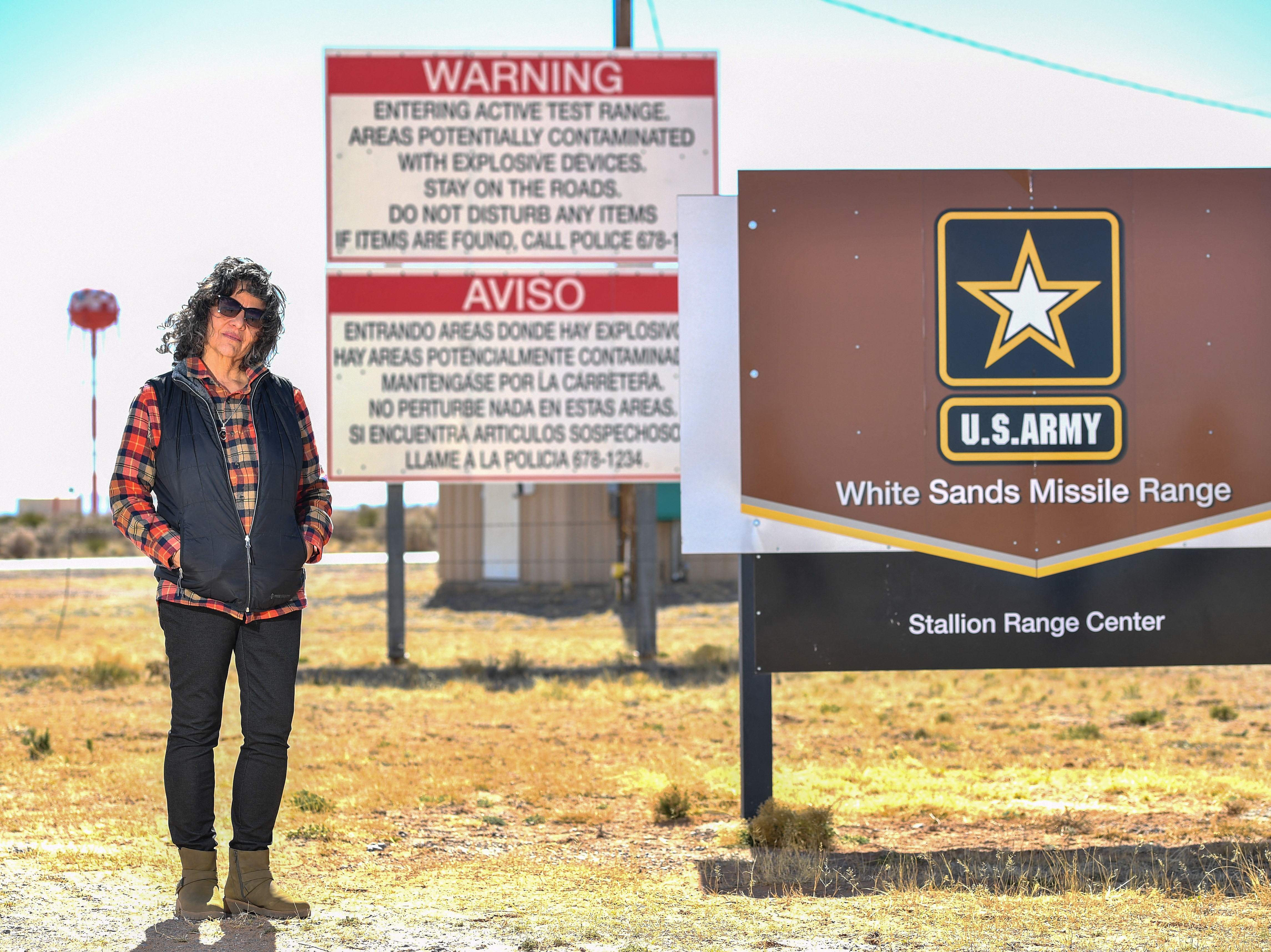Tina Cordova poses in front of the entrance of White Sands Missile Range where Trinity test site is located. Cordova who is one of five generations in her family diagnosed with cancer since 1945, and runs the Tularosa Basin Downwinders Consortium. Cordova has been fighting for decades to secure compensation for those affected by the radiation from the Trinity test.