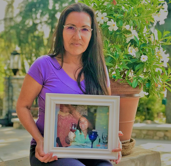Maria E. Garay-Serratos holds a framed photograph of her mother, who died after suffering decades of domestic violence. Scientists are trying to understand how domestic violence damages the brain. (Maria E. Garay-Serratos)
