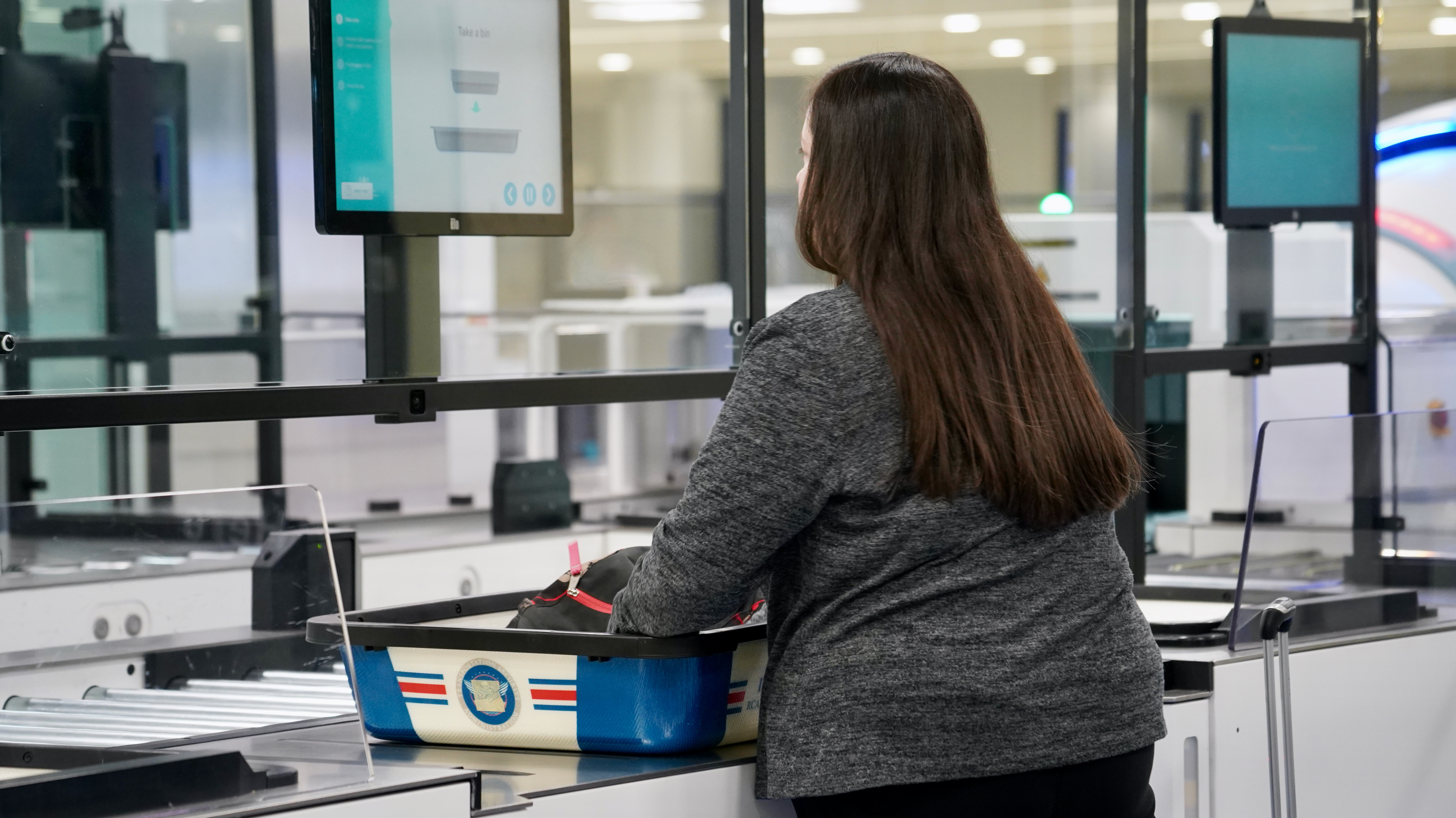 The new airport security prototype has a video monitor that provides step-by-step instructions for passengers to complete screening at their own pace.