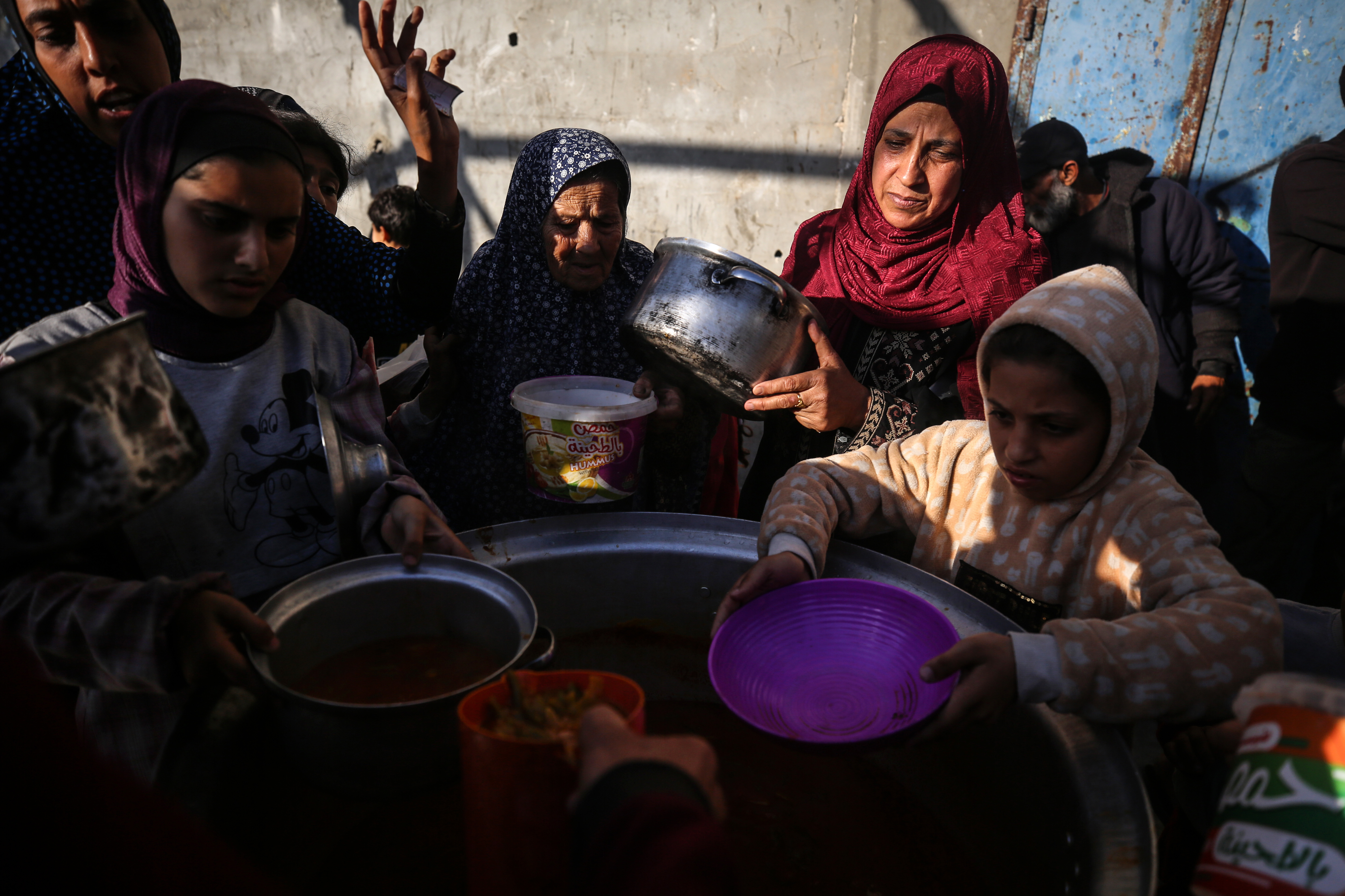 Displaced Palestinians gather to receive food donated by a charity before an iftar meal, the breaking of fast, on the second day of the Muslim holy fasting month of Ramadan, in Deir al-Balah, central Gaza Strip, Tuesday, amid ongoing battles between Israel and the militant group Hamas. (Majdi Fathi/NurPhoto via Getty Images)