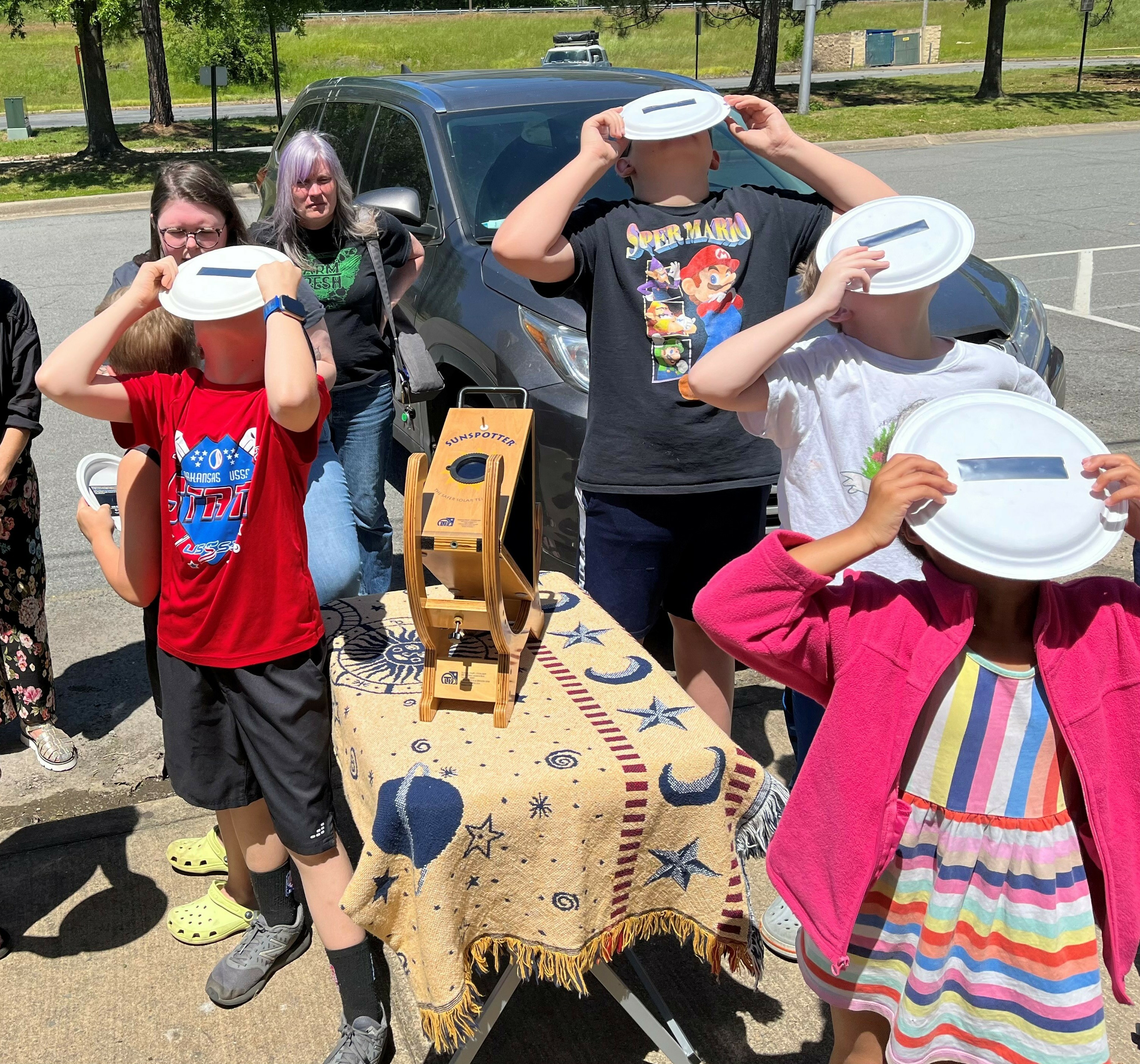 Children use solar filters to safely view the sun in North Little Rock, Ark., in May. The event is part of the Central Arkansas Astronomical Society's public education effort to prepare for this year's April 8 total solar eclipse. (Central Arkansas Astronomical Society)