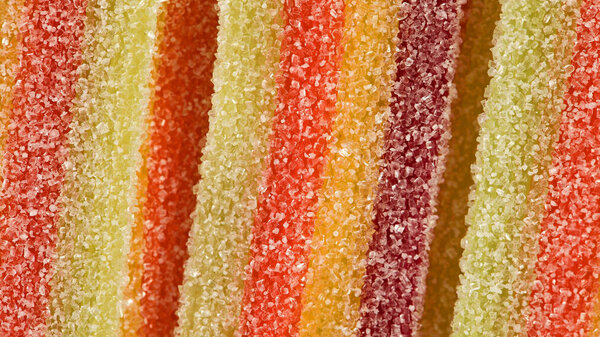 A close-up image of candy strips coated in sugar. 