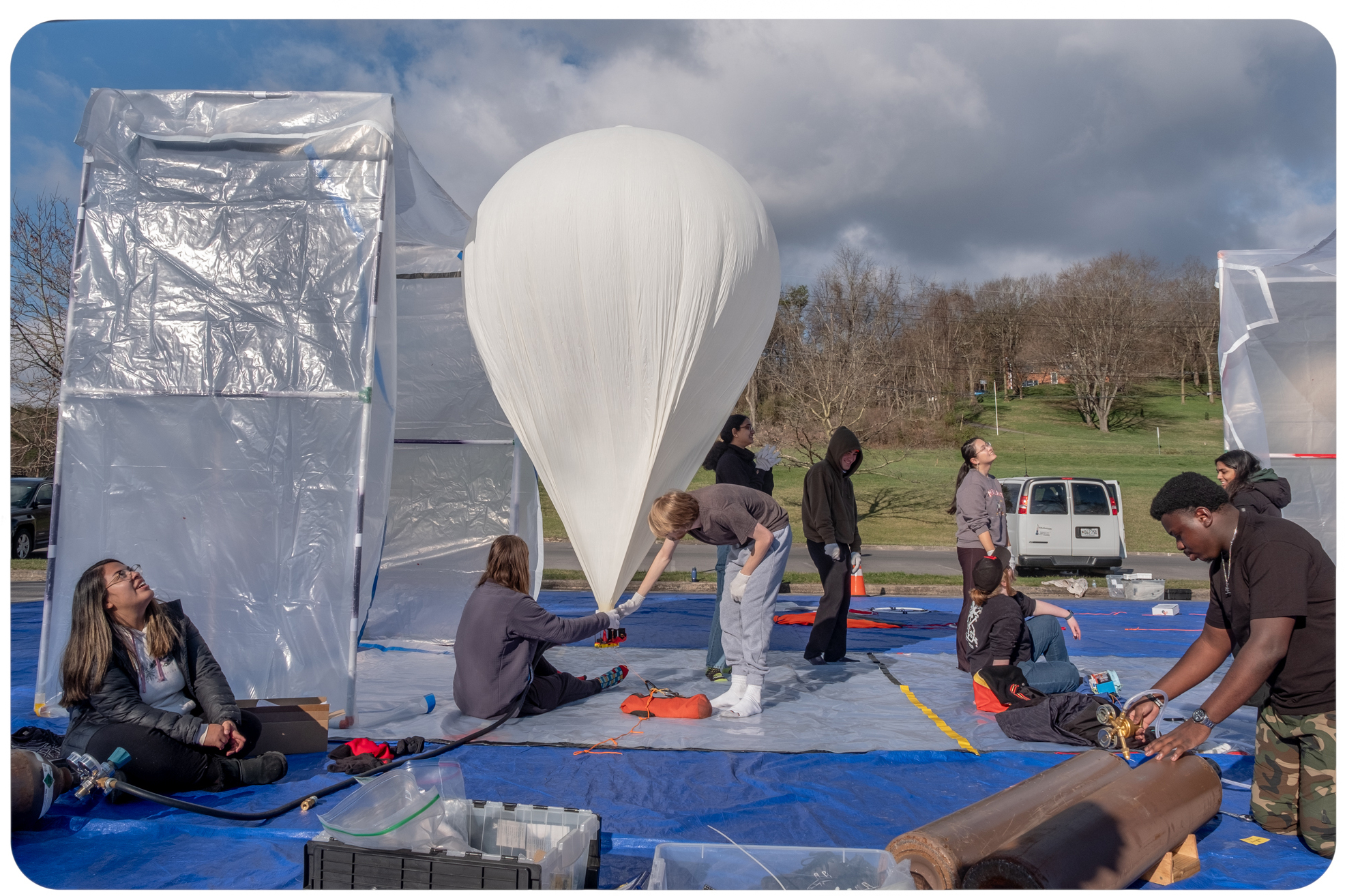 Student volunteers prepare a balloon for a morning launch in Cumberland, Md. On April 8, eclipse day, hundreds of balloons will be launched into the path of the eclipse to study the atmosphere. (Meredith Rizzo for NPR)