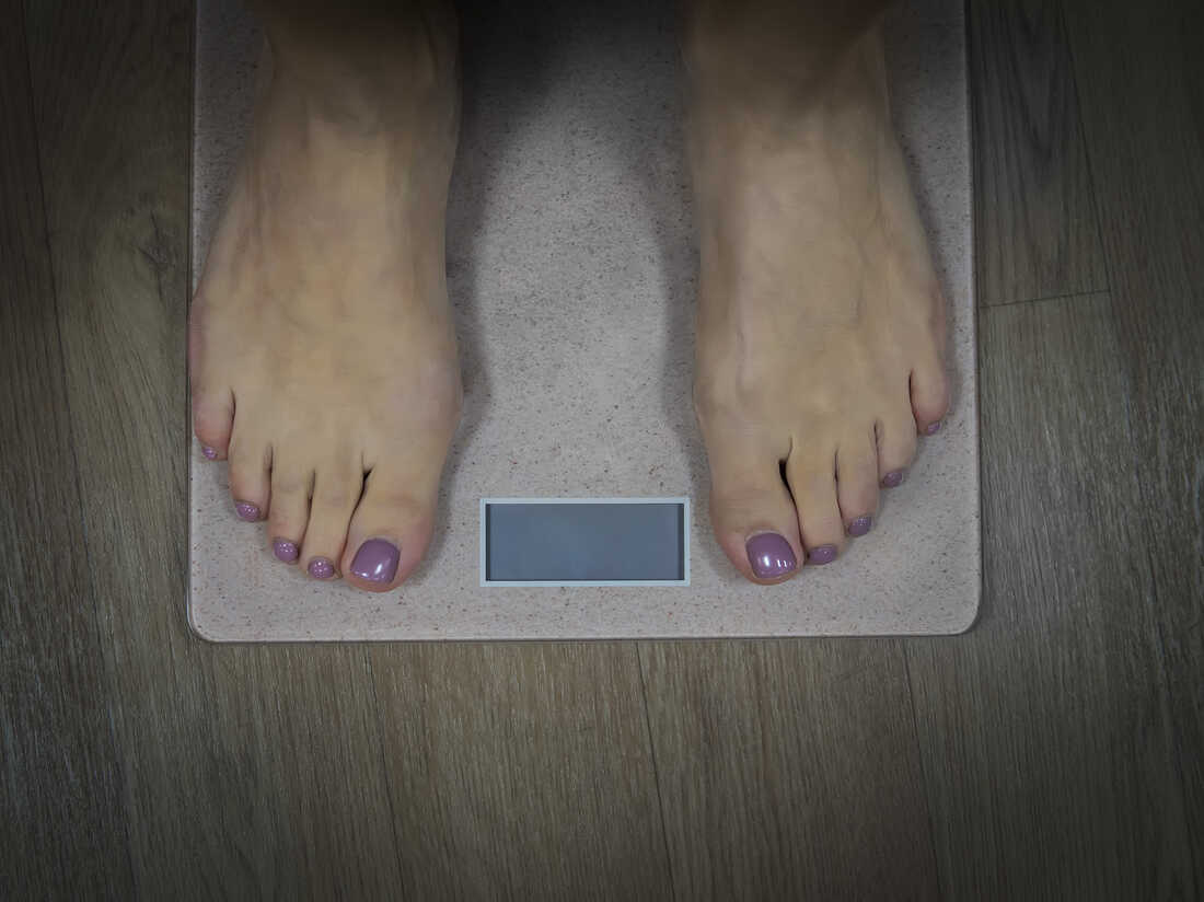Ozempic. Weight loss. Close up to female bare feet with pedicure standing on scales with empty display. Woman standing on bathroom scale to check her weight. Weighting. Wellnes and health