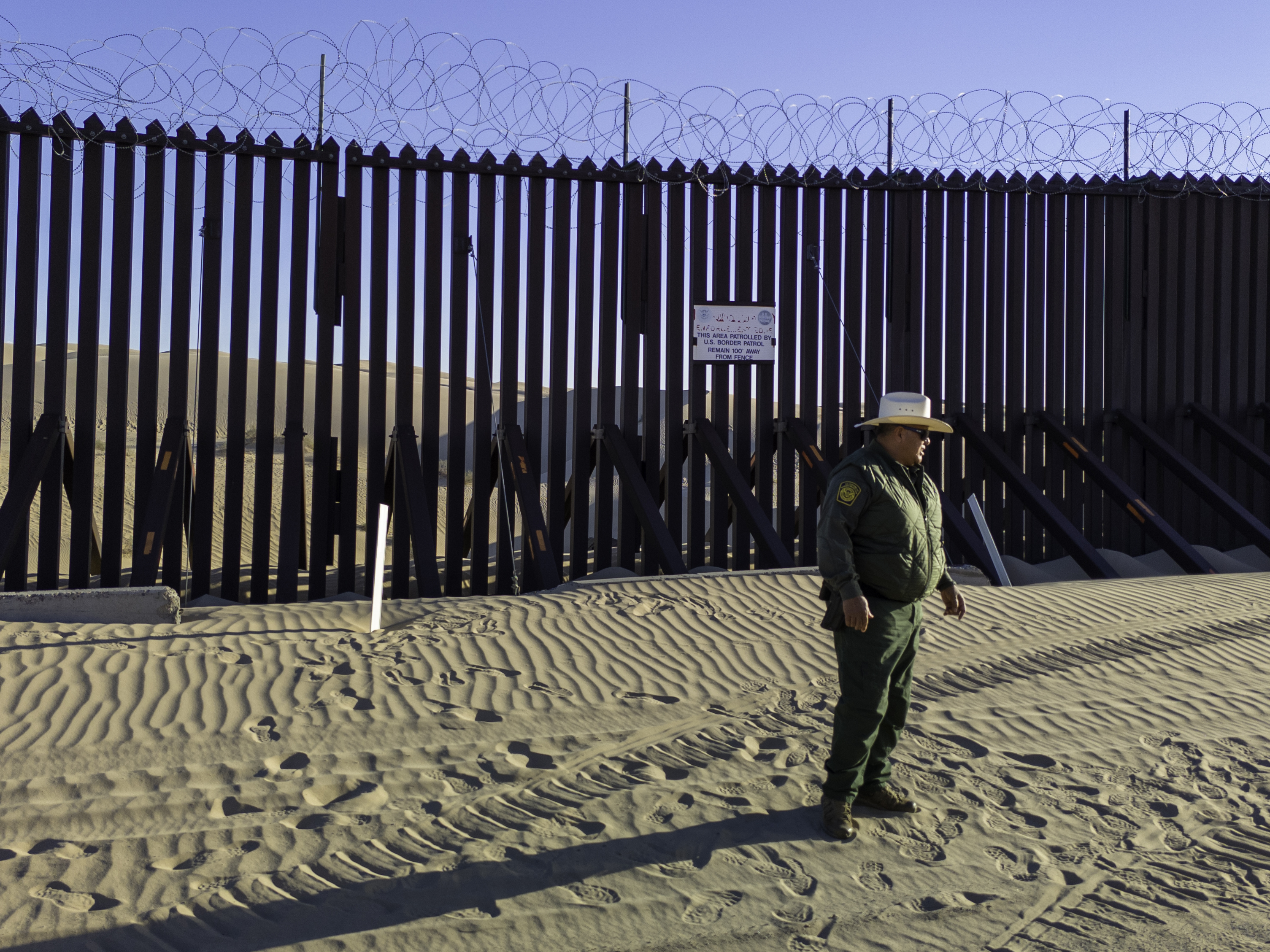 A U.S. Border Patrol agent stands near the border fence, which stretches through the Imperial Sand Dunes in California. (Getty Images)