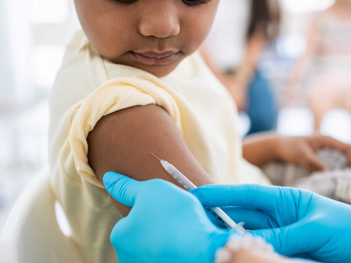 Close-up of a nurse in medical gloves giving an injection to a young patient.
