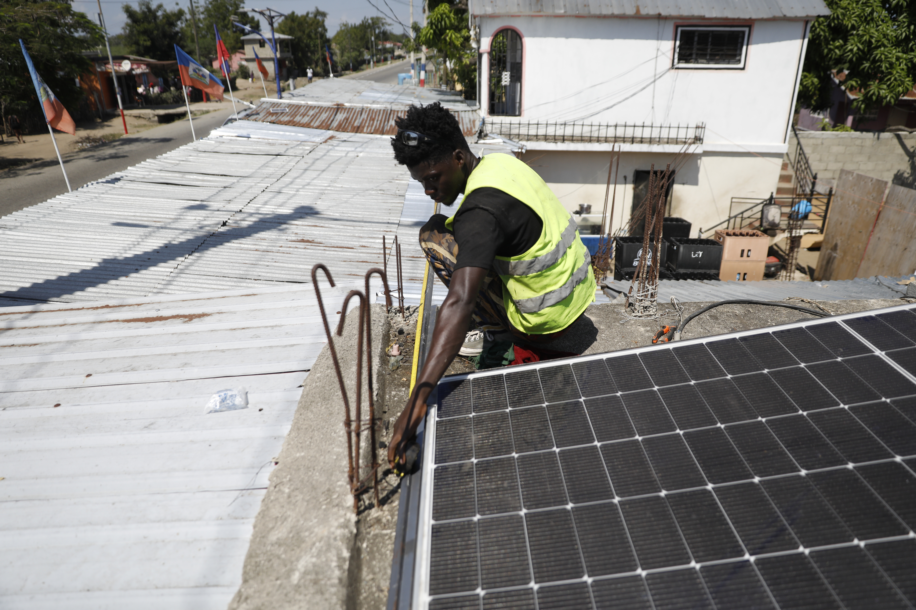 Rod Augustin, measures dimensions for solar panel installation at a local bar in Limonade, Haiti, on March 17, 2024.