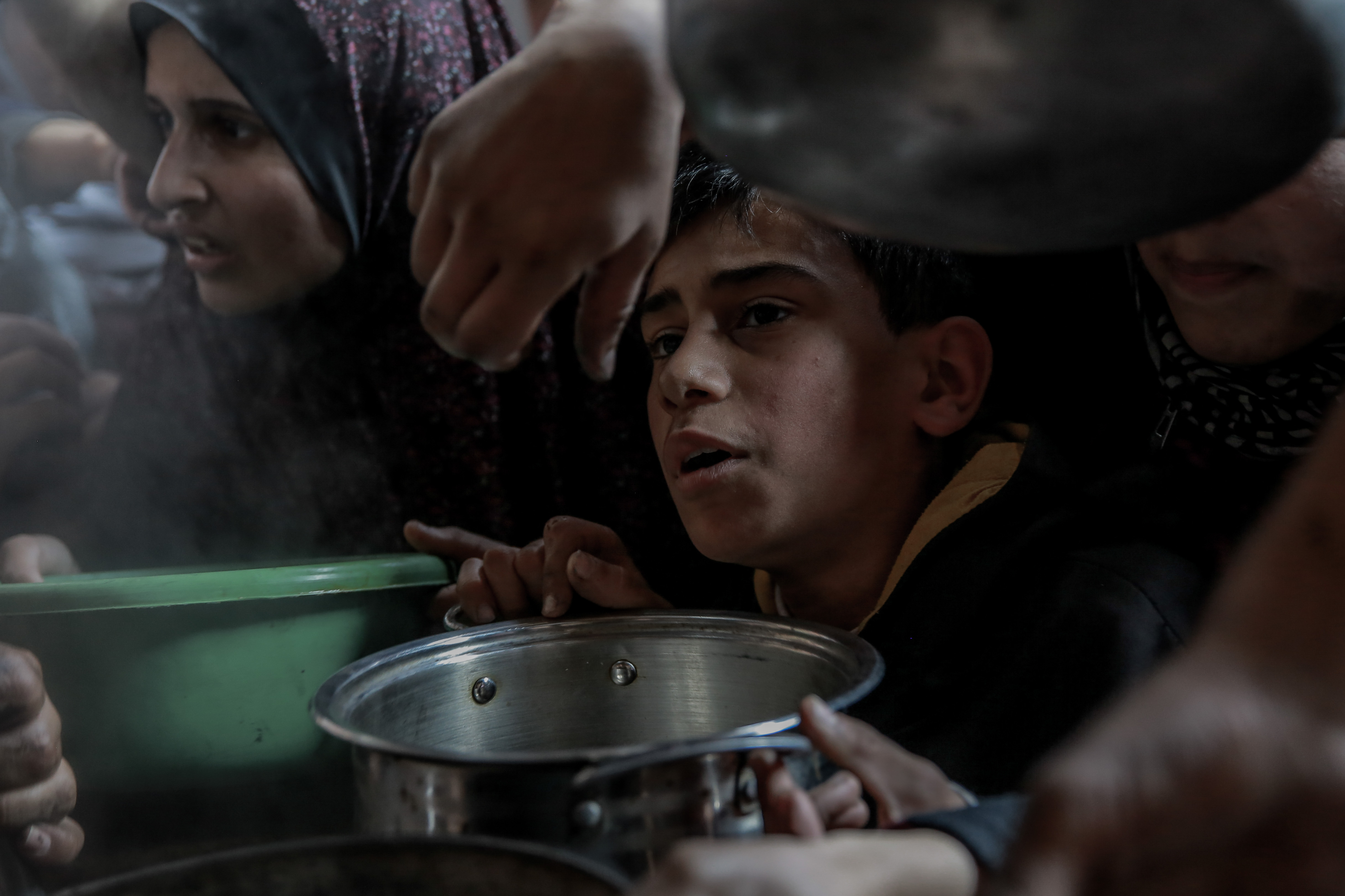 A Palestinian boy holds his bowl in a group of people awaiting food at a soup kitchen in Beit Lahia, Gaza Strip, Feb. 26.