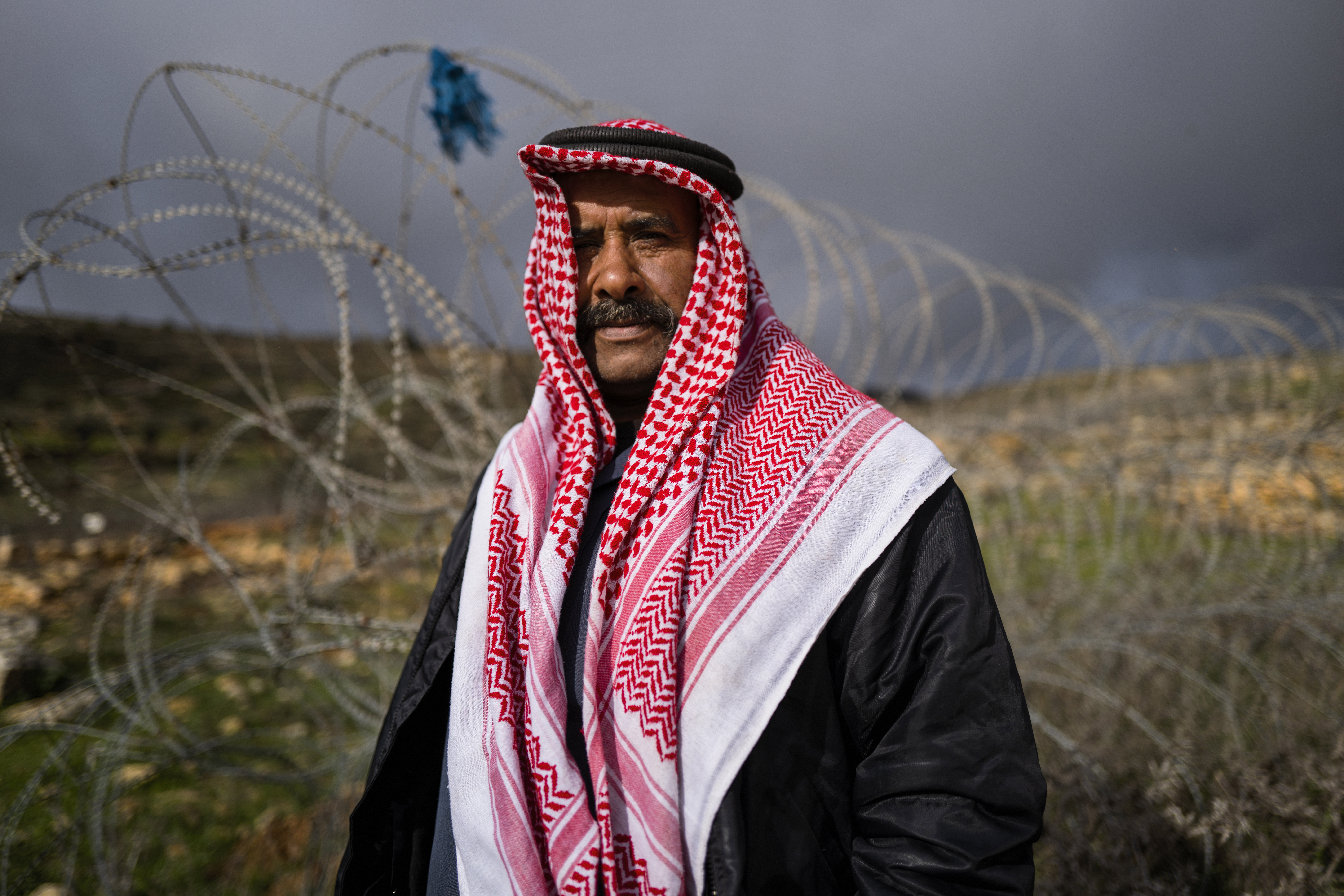 Sakher Abu Dahouk in front of the razor wire of the separation barrier that surrounds his land in Beit Hanina Al-Balad in the Israeli-occupied West Bank. His extended family has moved several times since 1948, as Israel seized territory in subsequent wars, redrew boundaries and built more Jewish settlements. "We still have deeds to our land," in what's now southern Israel, he says.