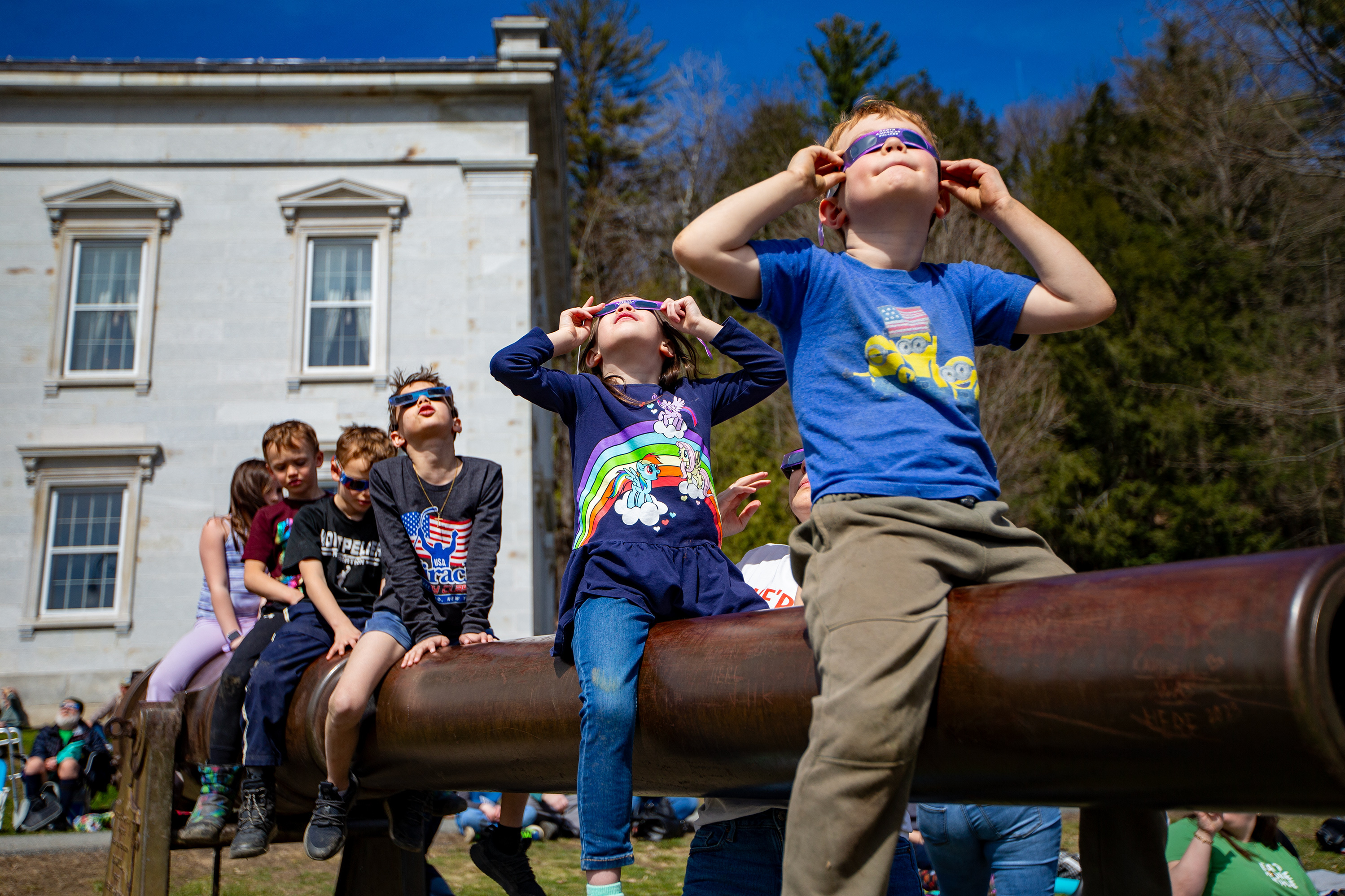 Kids watch the total eclipse begin sitting on a cannon out in front of the Vermont State House in Montpelier, Vermont.