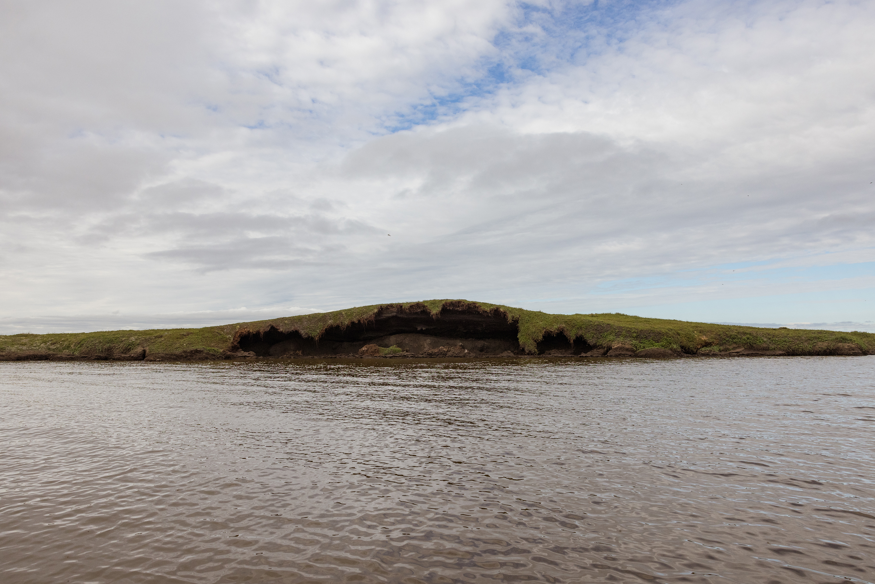 A tundra island near Kasigluk erodes, exposing thawing permafrost. Two months after this photo was taken, the opening collapsed completely.