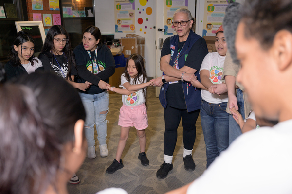 Girls and their leaders hold hands and sing songs as the closing activity to their weekly Troop 6000 meeting, held at the Row Hotel.