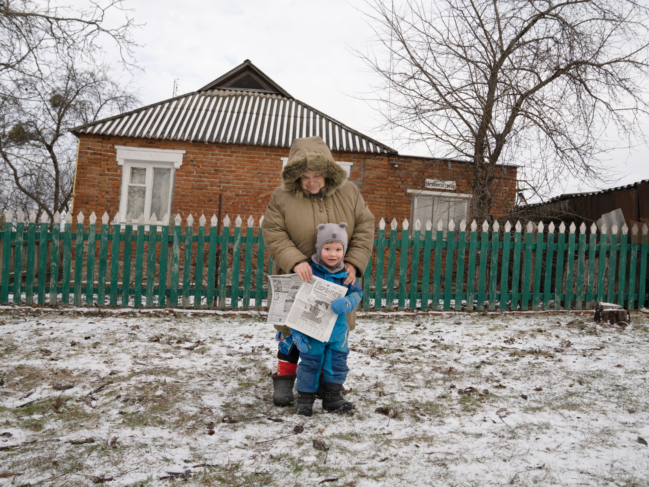 Olena Yeremenko stands with her grandson Nazar, 3, after picking up an edition of Peremoha.