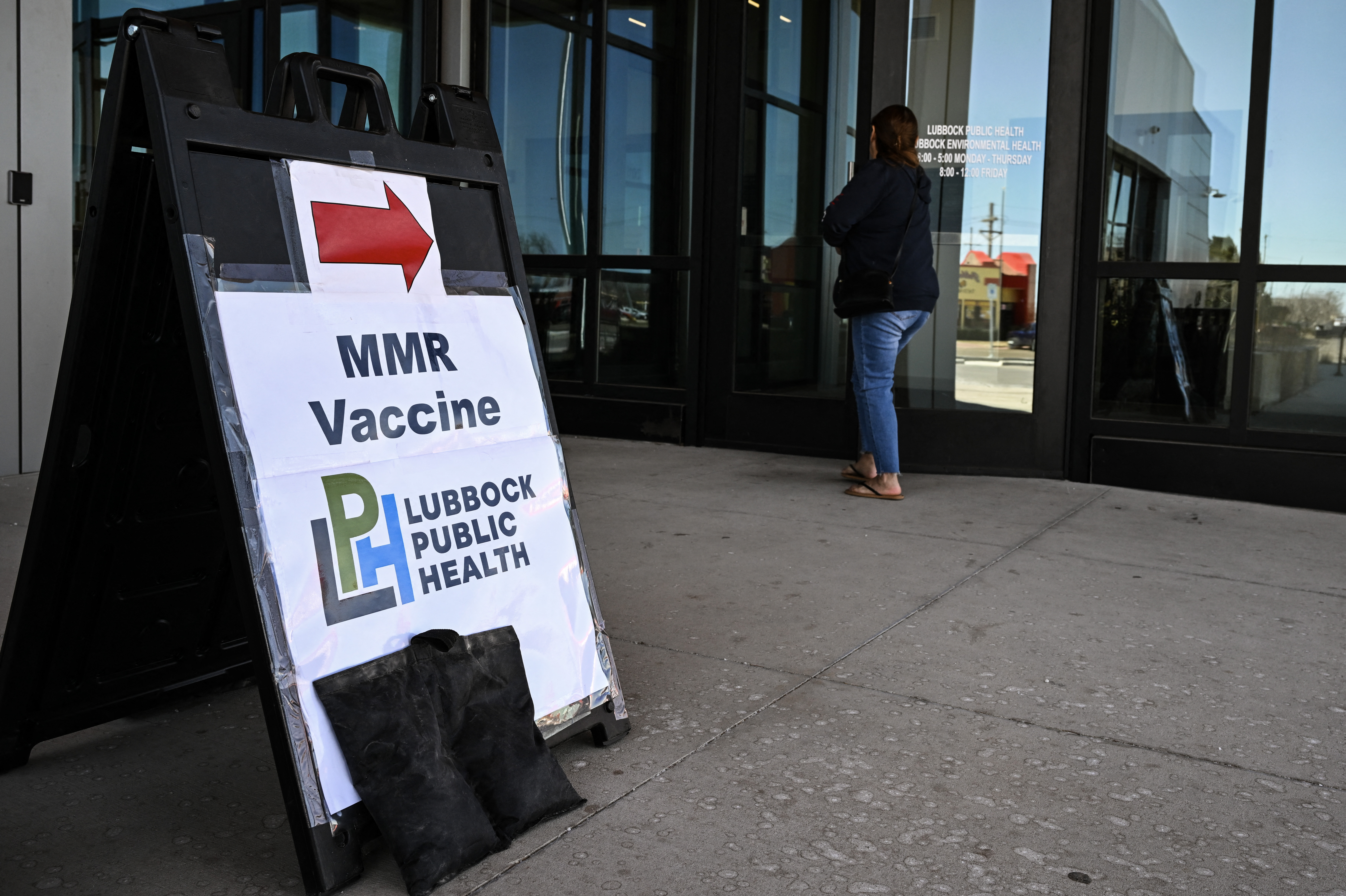 A person walks past a sign at a health center where the MMR (measles-mumps-rubella) vaccine is administered in Lubbock, Texas earlier this year.