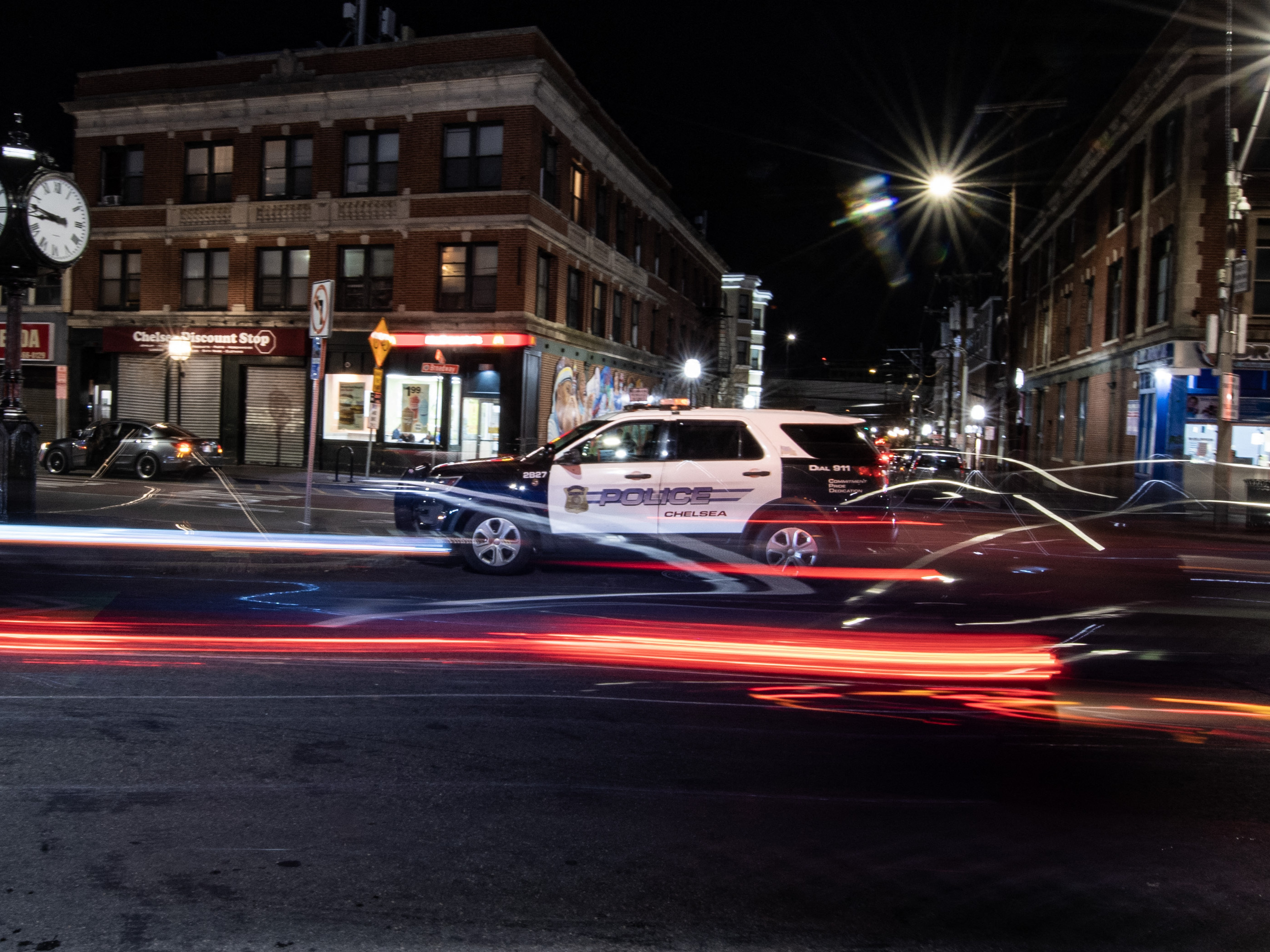 Cars speed by a parked police cruiser in Chelsea, Massachusetts, on April 21, 2023.