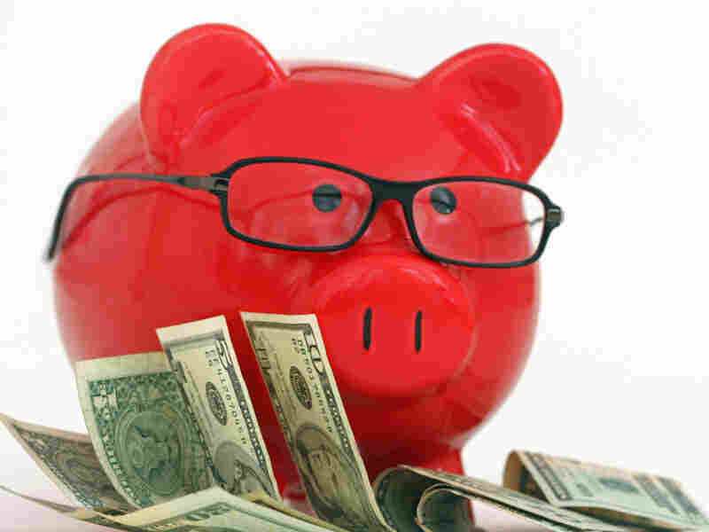 A red piggy bank wearing glasses and standing on money. iStockphoto.com