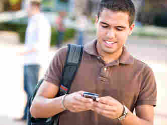 A young Hispanic man checks his mobile phone.