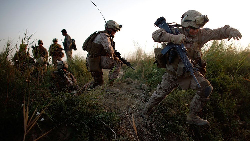 Lance Cpl. Chris Garcia and other members of Golf Company cross an irrigation ditch as the 2nd Battalion, 8th Marine Regiment moves into Helmand province in July during a major offensive against the Taliban stronghold in southern Afghanistan. (NPR)