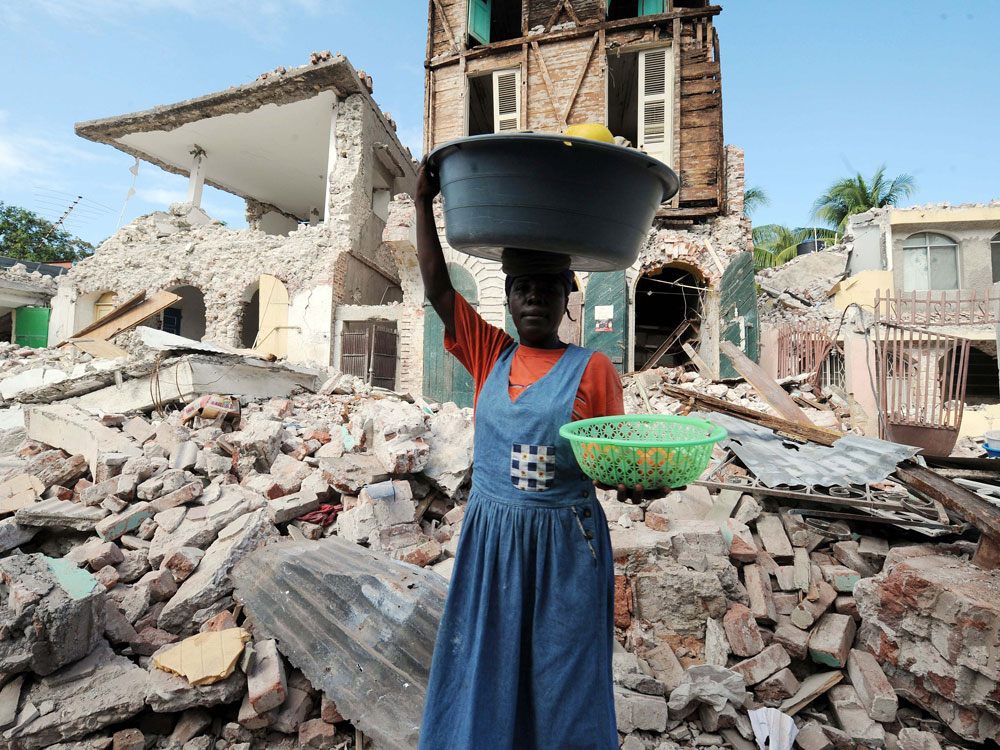 A Haitian vendor walks past a collapsed building in Jacmel on Tuesday, a week after the country was shattered by a massive magnitude-7 earthquake. The Haitian government said 70,000 bodies had been buried in mass graves since the quake flattened much of the impoverished Caribbean nation, triggering a massive humanitarian crisis. Officials fear the eventual death toll could top 200,000.