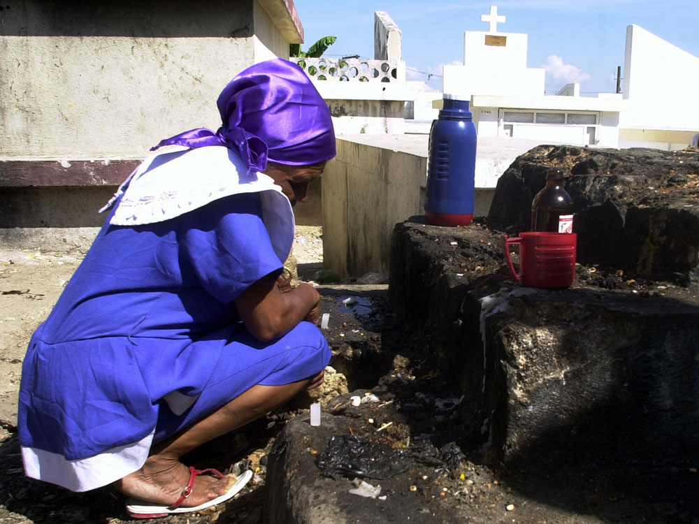 A Haitian woman observes a moment of silence after putting coffee and beer at the grave of her family during celebrations of the Day of the Dead in November 2006.  The two-day celebration honors ancestors by visiting their graves and bringing their favorite foods and drinks. (AFP/Getty Images)