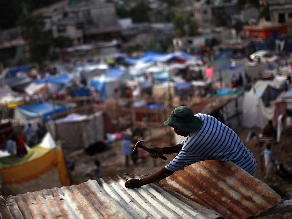 In the Petionville neighborhood, a man nails a corrugated roof to a temporary structure above a makeshift camp for residents who lost their homes in the devastating earthquake. (Getty Images)