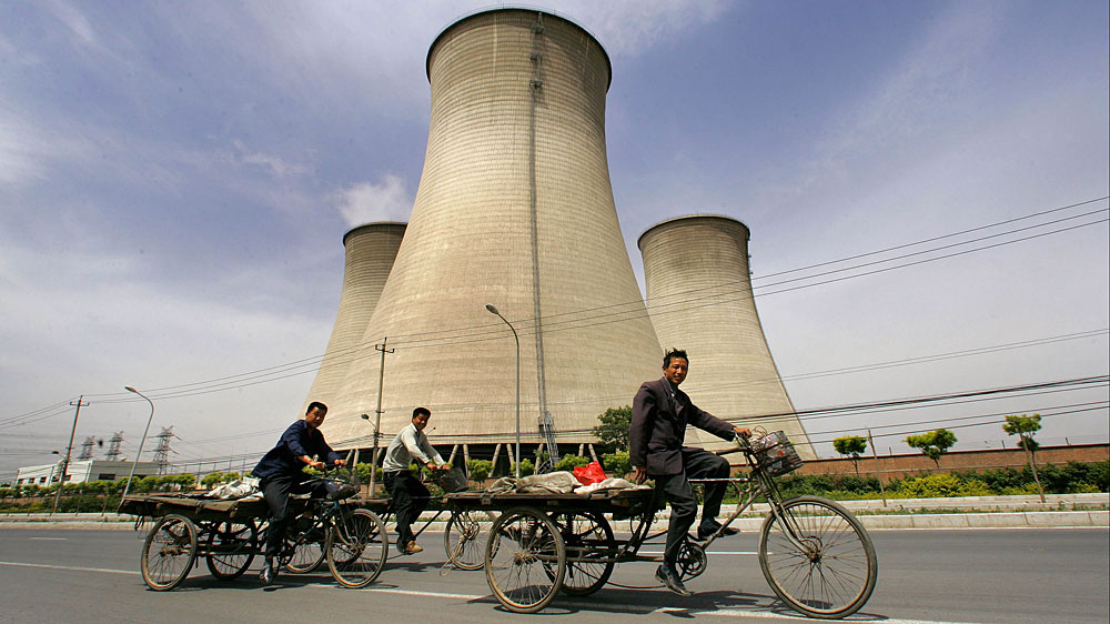 Workers ride past cooling towers at a coal-fired power plant on the outskirts of Beijing. Such power plants are at the center of a debate about the future of energy production in China and the U.S. (AFP/Getty Images)