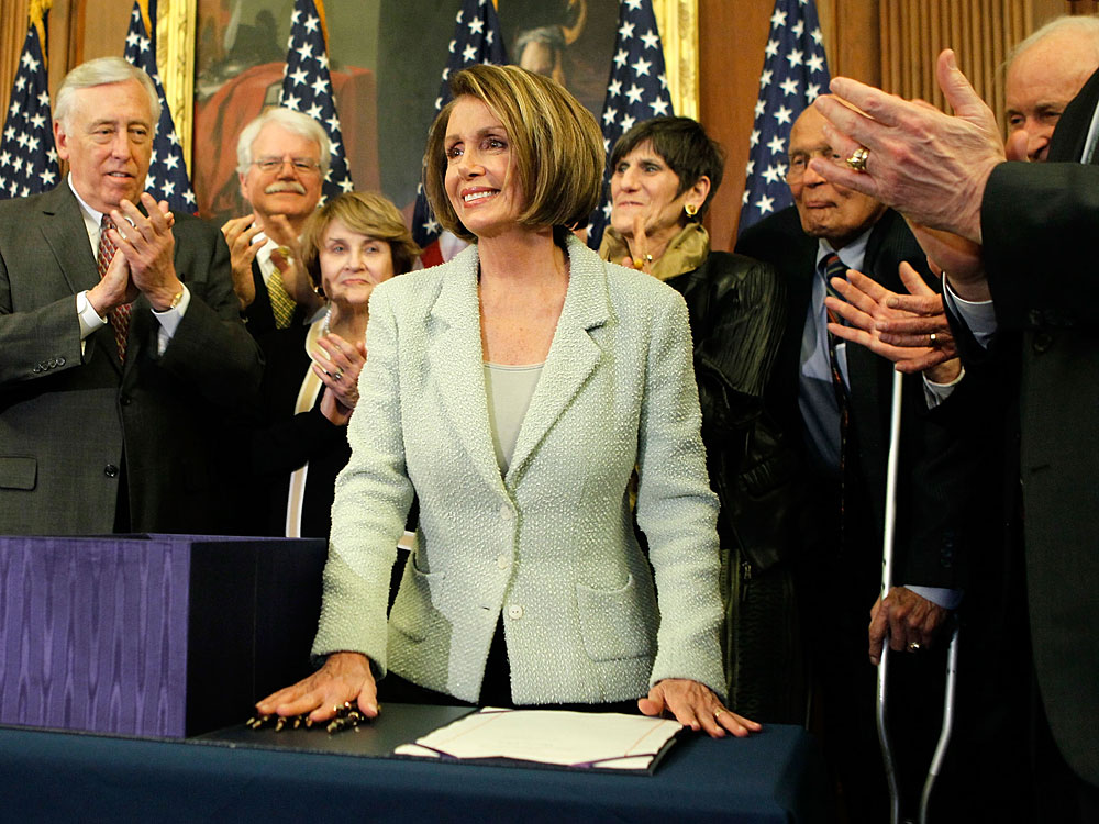 Speaker of the House Rep. Nancy Pelosi  (center) is lauded by fellow Democrats after signing the health care overhaul bill Monday. (Getty Images)