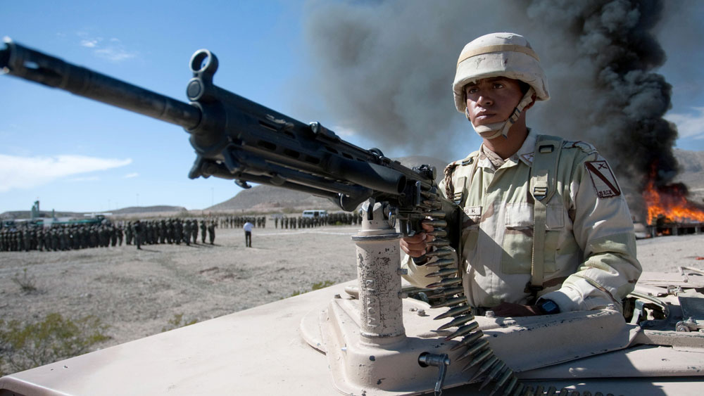A Mexican soldier stands guard as a haul of marijuana and cocaine are incinerated in the background in November 2009. Fighting among the drug cartels — and between government forces and the cartels — has cost nearly 24,000 Mexican lives since late 2006. (AFP/Getty Images)
