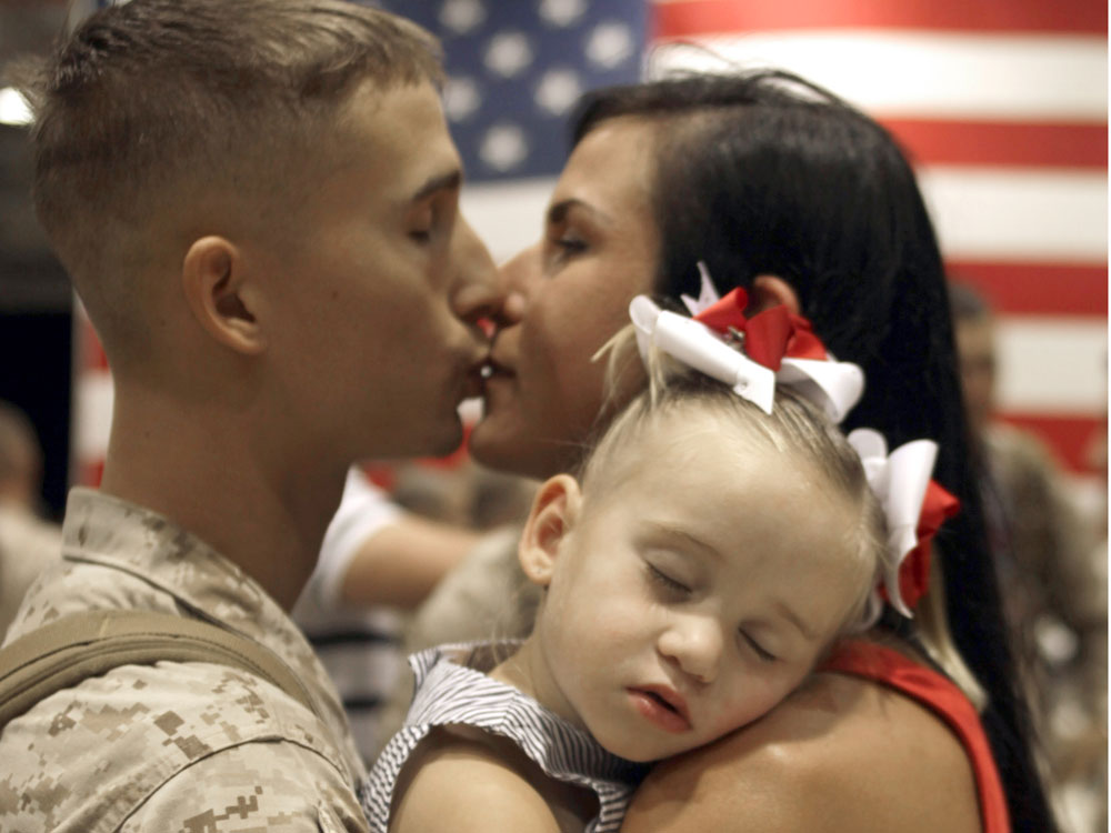 Andrew Thai with 1st Battalion/ 3rd Marines, Charlie Company, kisses his wife Sarah holding daughter Mikalah upon his return to Hawaii early June 14, 2010, following a seven-month deployment in southern Afghanistan. (AFP/Getty Images)