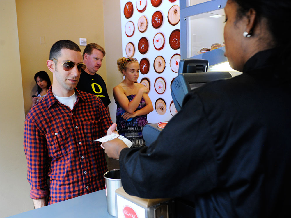 Andrew Lowenthal (left) receives his $50 gift card from Red Velvet Cupcakery employee Lauren Knight at the company's store in Washington, D.C. More than 2,000 customers purchased the cards for $25 through a deal with LivingSocial. (NPR)
