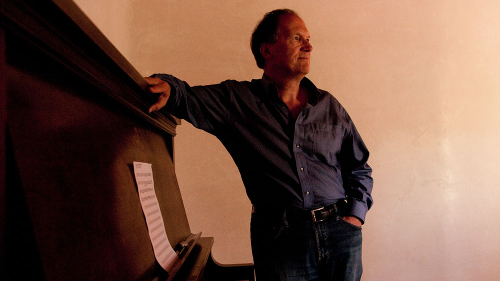Robert Kyr spends late nights at an upright piano, writing down his music. (NPR)