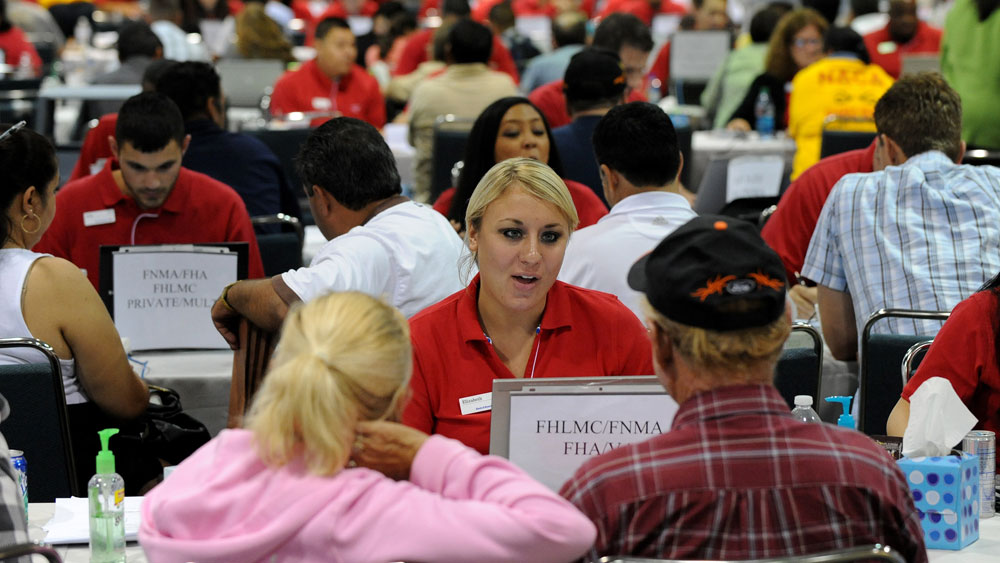Homeowners speak with bank consultants in Los Angeles in September at an event put on by the  Neighborhood Assistance  Corporation of America. The organization's CEO, Bruce Marks, says foreclosure suspensions at three major banks and several states may actually help stabilize the economy. (AFP/Getty Images)
