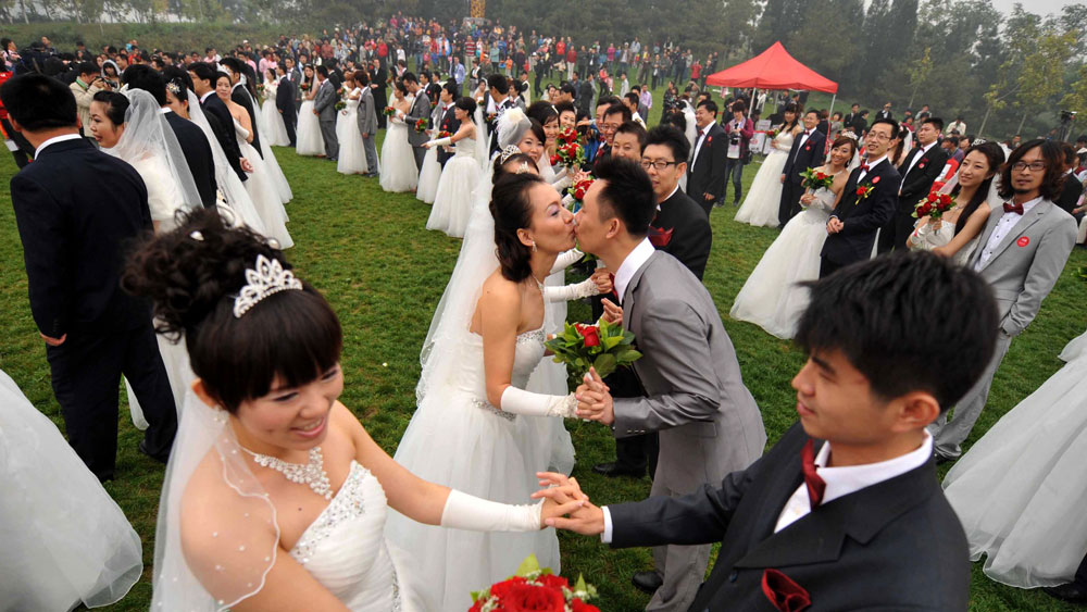 Despite China's advances over the past few decades, when it comes to marriage, tradition holds sway. Here, 200 newlywed couples pose at the National Stadium in Beijing, Oct. 10, 2010. (AFP/Getty Images)