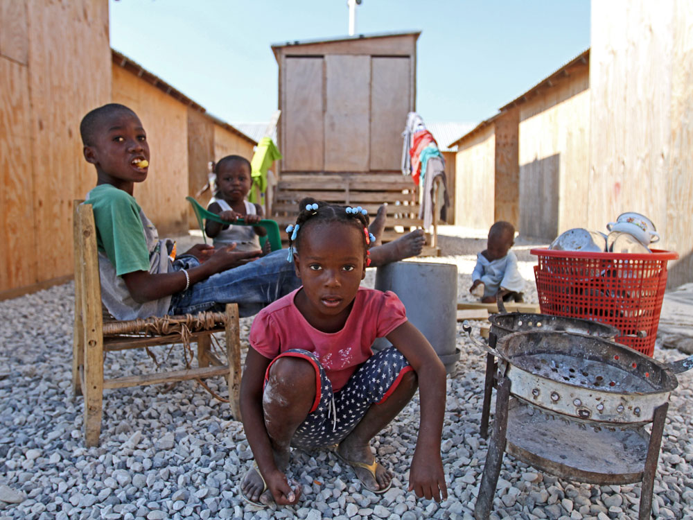 Children play in front of latrines built by the American Red Cross