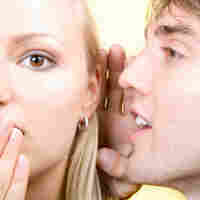 man whispering to a woman.