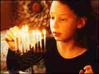 Girl lights menorah.
