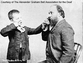 A man teaches a young, deaf boy the letter N